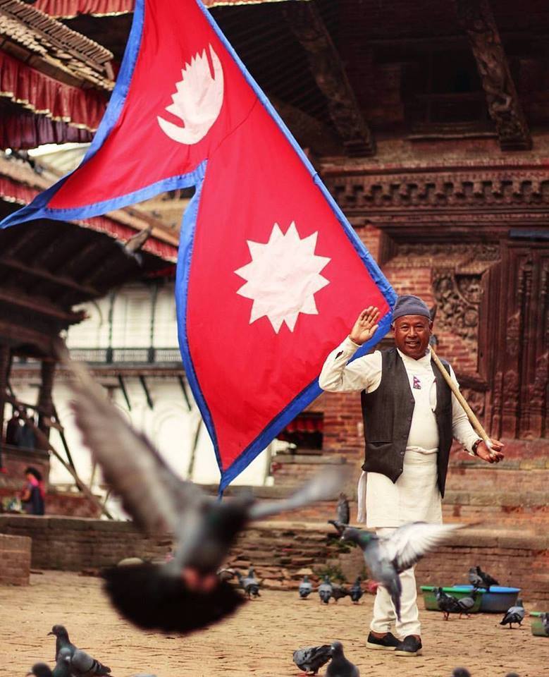 Nepali man carrying national flag.